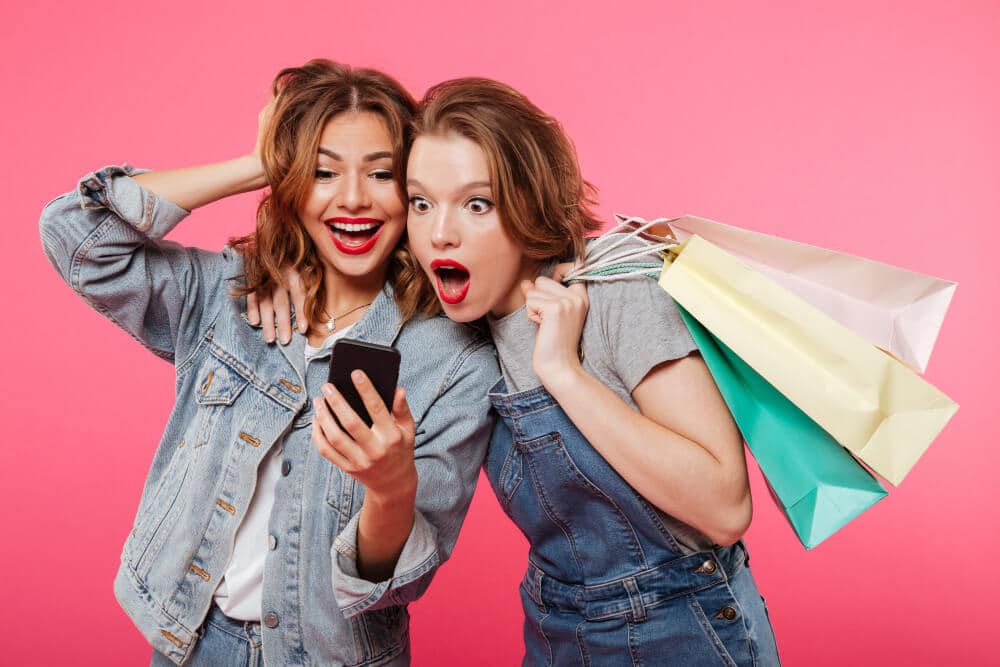 how to stop impulsive spending | Two ladies looking at promotion on phone